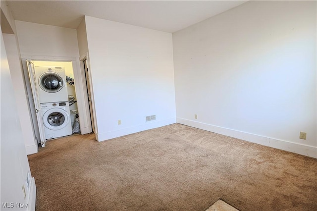 laundry area featuring carpet and stacked washer / drying machine