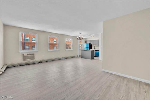 unfurnished living room with a chandelier, sink, a wall mounted AC, and light hardwood / wood-style floors