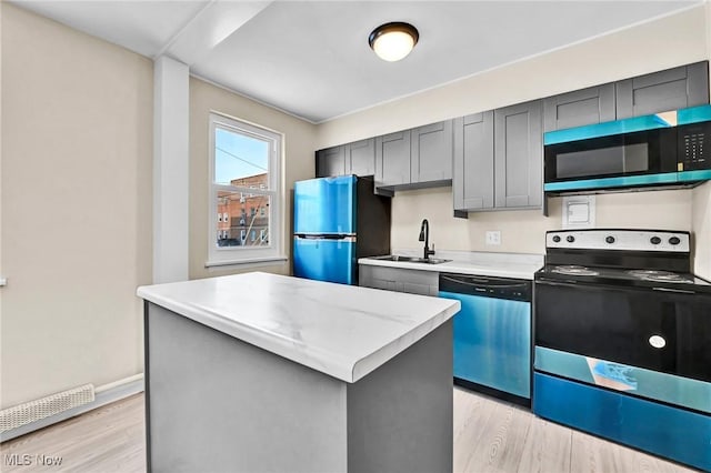 kitchen featuring stainless steel appliances, sink, a kitchen island, and light wood-type flooring