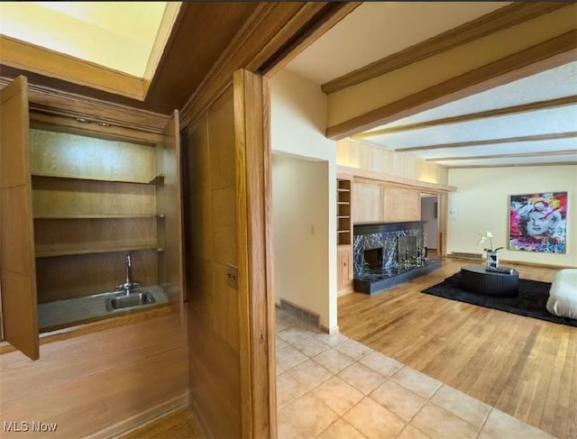 interior space with built in features, a high end fireplace, light tile patterned flooring, light brown cabinetry, and beamed ceiling