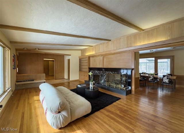 living room with hardwood / wood-style flooring, a fireplace, beam ceiling, and a textured ceiling