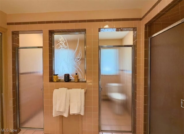 bathroom with walk in shower and tile walls