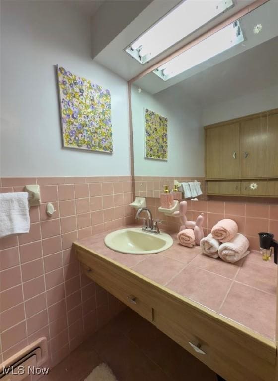 bathroom with sink, tile walls, and a skylight