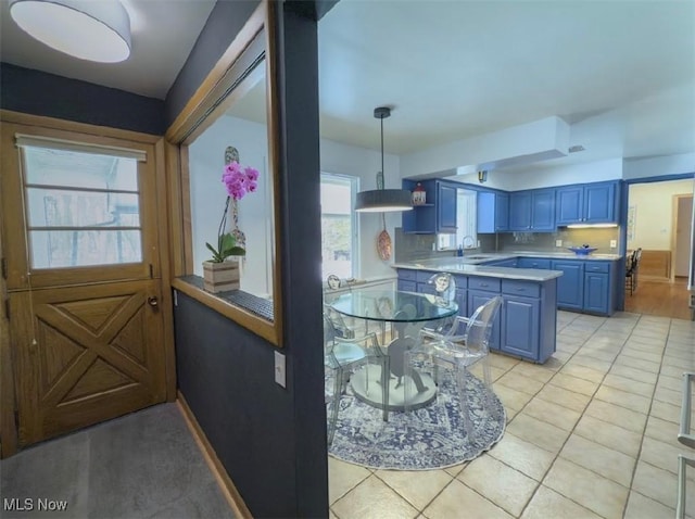 kitchen featuring sink, decorative light fixtures, blue cabinetry, and light tile patterned flooring