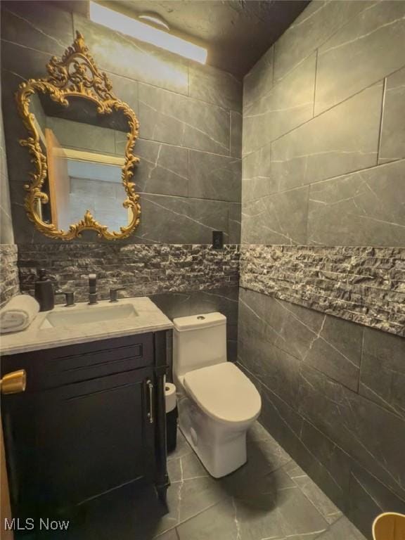 bathroom with vanity, tile walls, and toilet