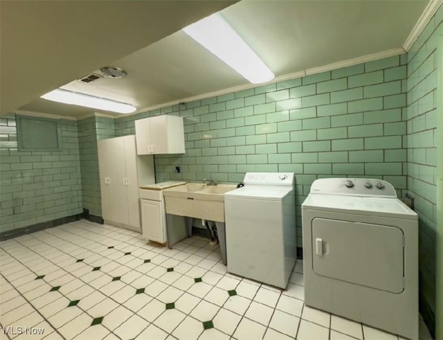 laundry area featuring cabinets, crown molding, tile walls, and washer and clothes dryer