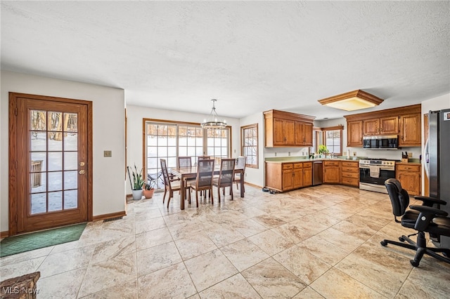 kitchen with a notable chandelier, stainless steel appliances, hanging light fixtures, and a textured ceiling