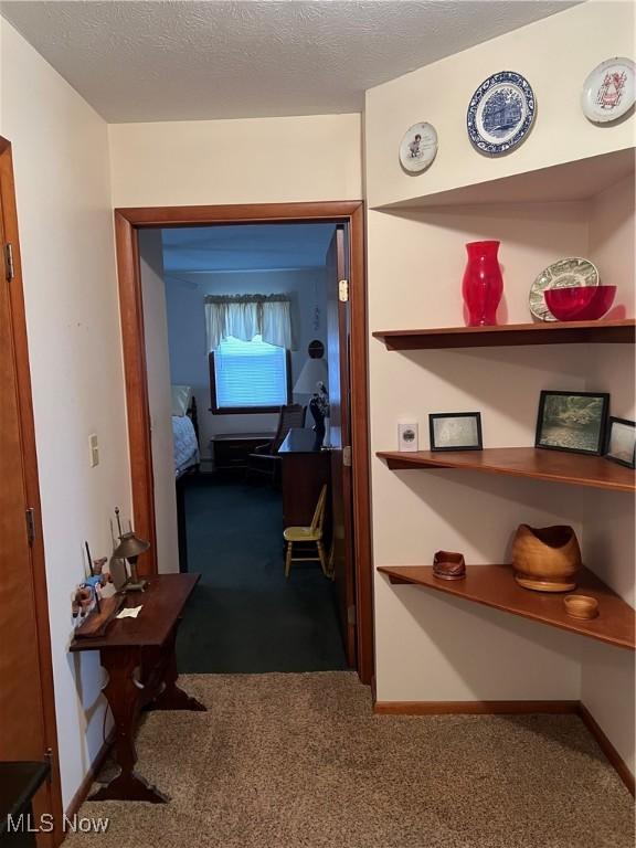 corridor featuring a textured ceiling and carpet flooring