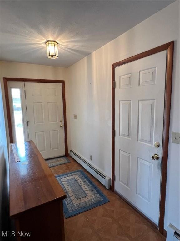 foyer entrance featuring a baseboard heating unit and dark parquet floors