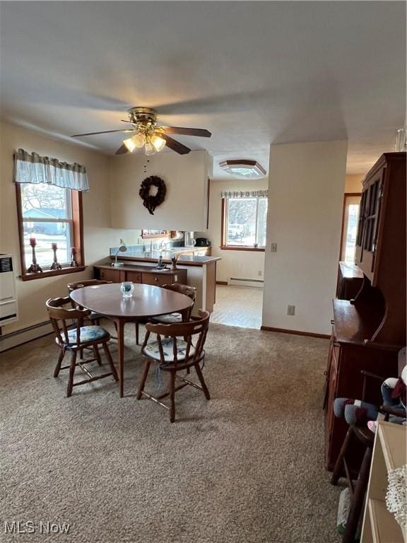 carpeted dining room featuring baseboard heating, ceiling fan, and a healthy amount of sunlight