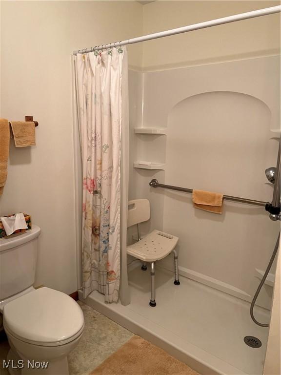 bathroom featuring tile patterned flooring, toilet, and a shower with shower curtain