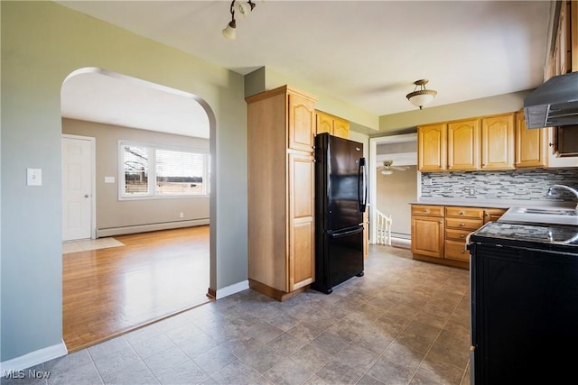 kitchen featuring light brown cabinetry, sink, black appliances, a baseboard heating unit, and backsplash