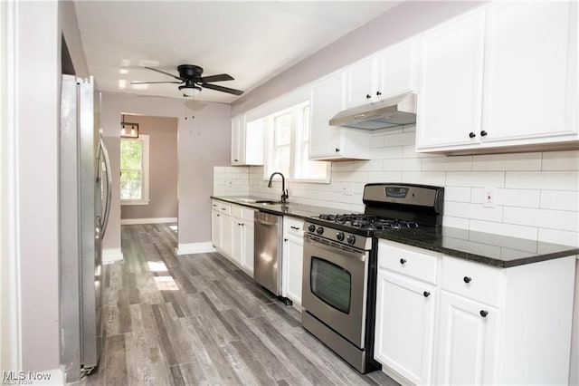 kitchen featuring sink, stainless steel appliances, dark stone counters, and white cabinets