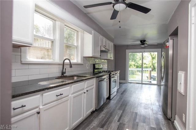 kitchen with sink, appliances with stainless steel finishes, white cabinetry, dark stone countertops, and tasteful backsplash