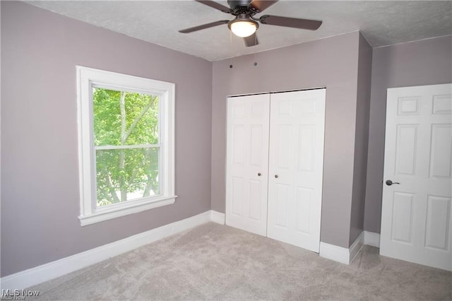 unfurnished bedroom featuring ceiling fan, light colored carpet, a closet, and a textured ceiling