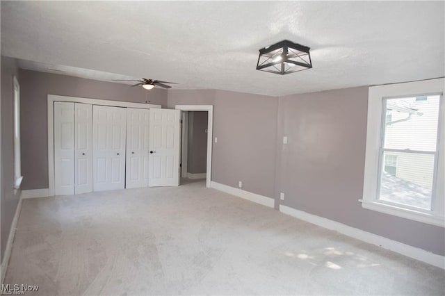 unfurnished bedroom with ceiling fan, carpet flooring, a textured ceiling, and a closet