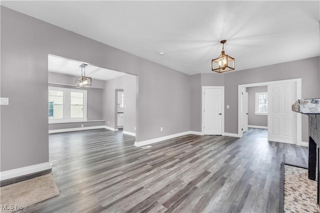 unfurnished living room with an inviting chandelier and hardwood / wood-style flooring