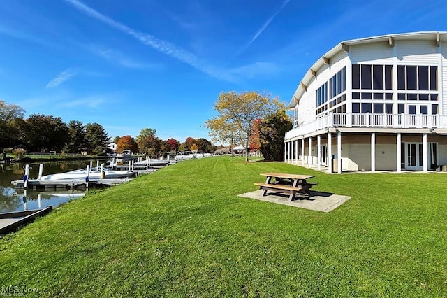 view of yard featuring a patio, a sunroom, a boat dock, and a water view