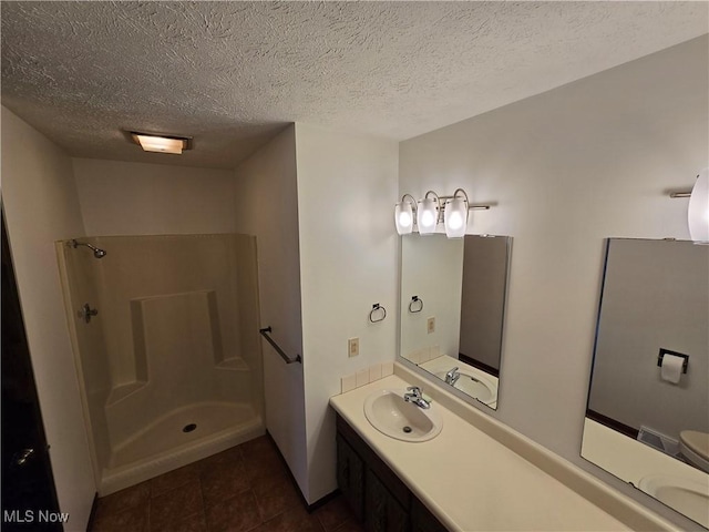 bathroom featuring walk in shower, vanity, tile patterned flooring, and a textured ceiling