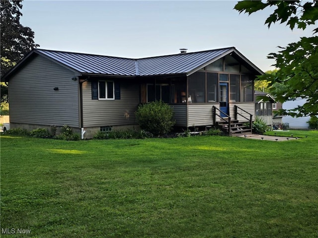 rear view of house featuring a sunroom and a lawn