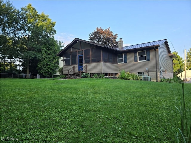 back of property featuring a lawn and a sunroom