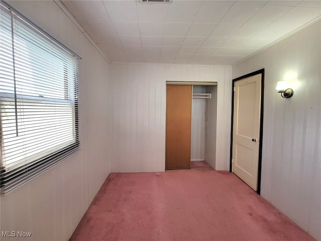 unfurnished bedroom with crown molding, light colored carpet, and a closet