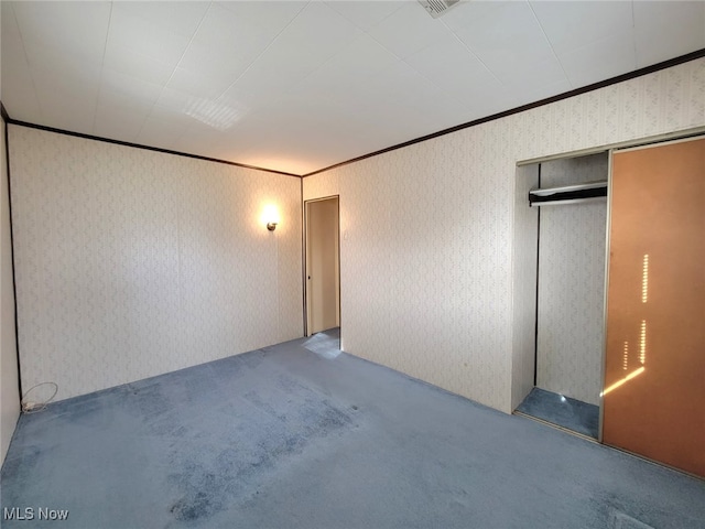 unfurnished bedroom featuring a closet, ornamental molding, and carpet