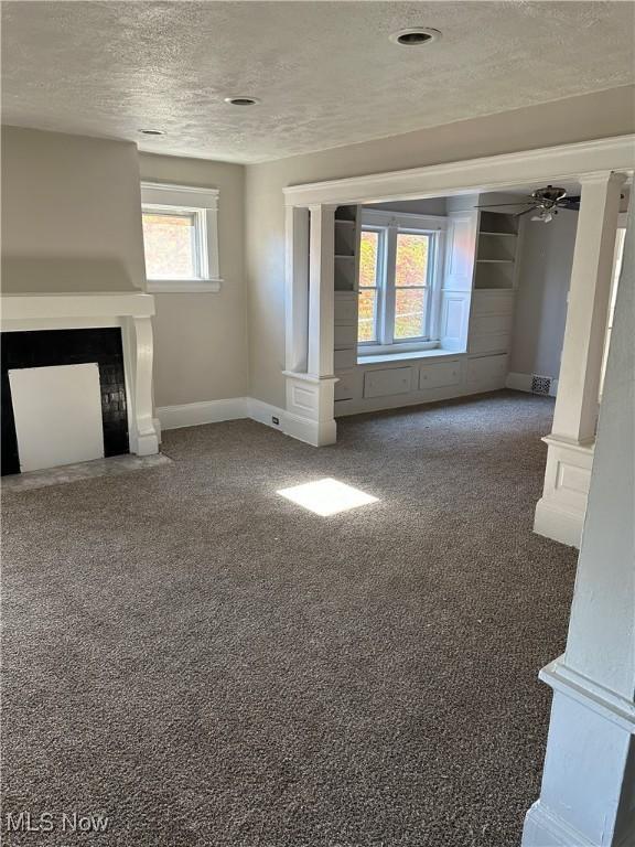 unfurnished living room featuring ceiling fan, dark carpet, and a textured ceiling