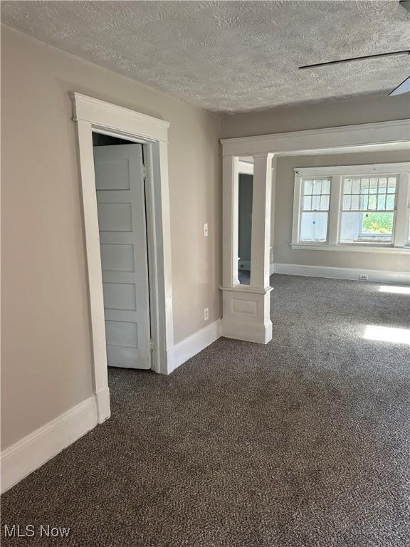 spare room featuring a textured ceiling and dark colored carpet