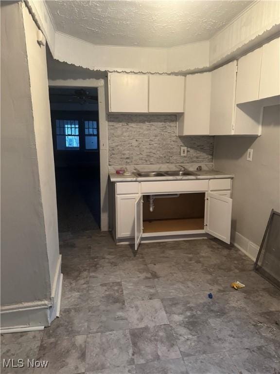 kitchen with sink, a textured ceiling, and white cabinets