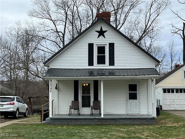 bungalow-style house with an outbuilding, a garage, a front lawn, and covered porch