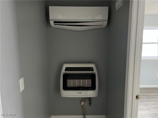 interior details featuring hardwood / wood-style flooring, heating unit, and a wall mounted AC