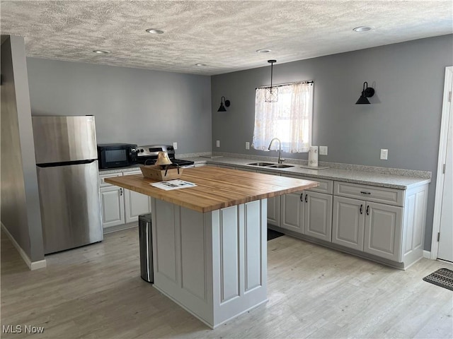 kitchen featuring stainless steel appliances, white cabinetry, sink, and wooden counters