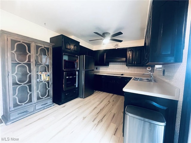 kitchen with sink, decorative backsplash, ceiling fan, black appliances, and light wood-type flooring