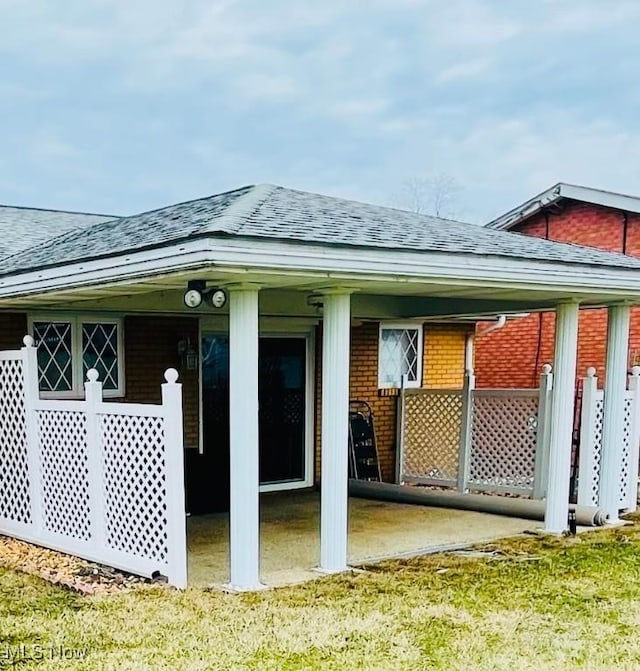 exterior space featuring brick siding and roof with shingles