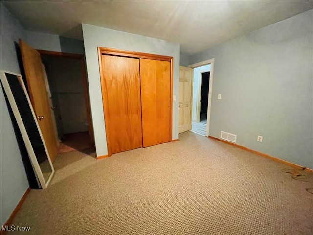 unfurnished bedroom featuring light carpet and a closet