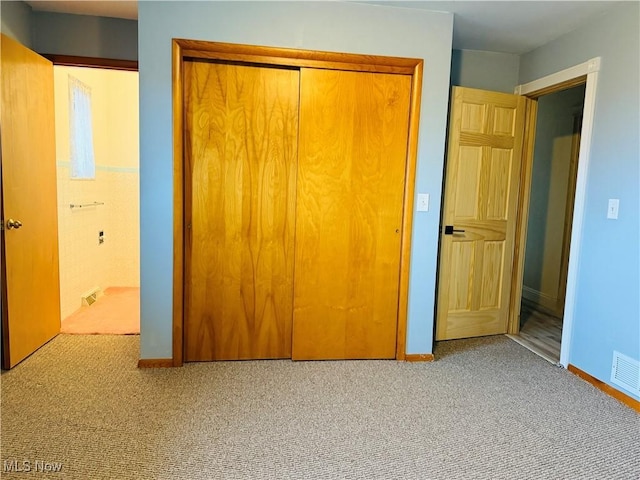 unfurnished bedroom featuring a closet, light colored carpet, visible vents, and baseboards