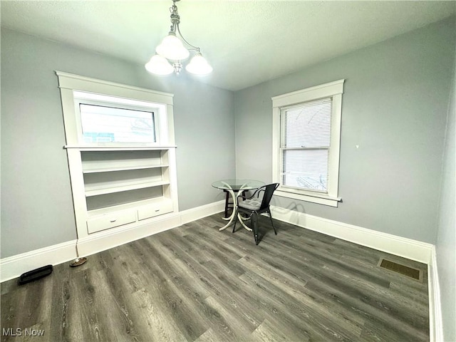 dining space with dark hardwood / wood-style floors and a chandelier