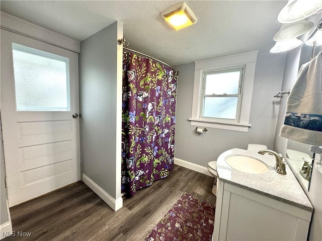 bathroom with wood-type flooring, vanity, a textured ceiling, and toilet