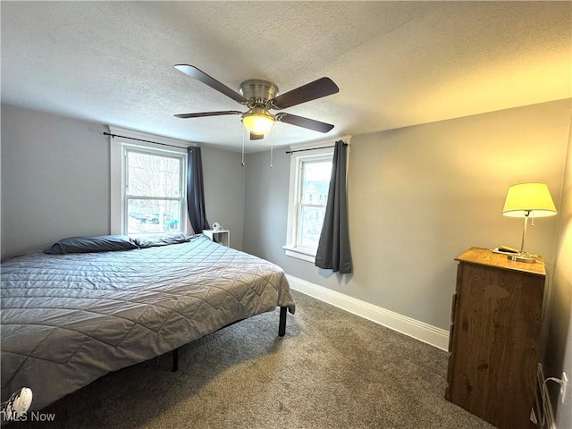 bedroom with multiple windows, ceiling fan, a textured ceiling, and dark colored carpet