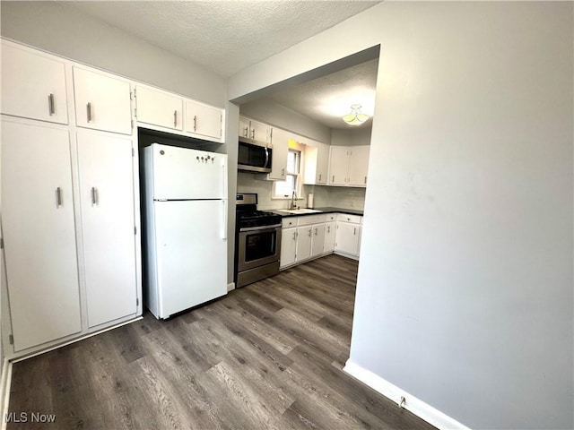 kitchen featuring sink, appliances with stainless steel finishes, a textured ceiling, white cabinets, and dark hardwood / wood-style flooring