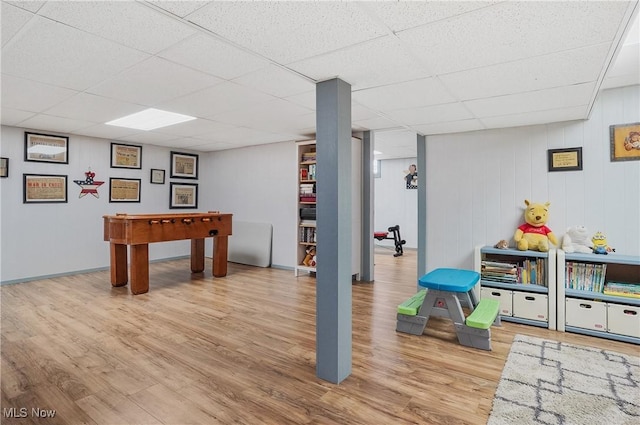 recreation room with a paneled ceiling and light hardwood / wood-style floors