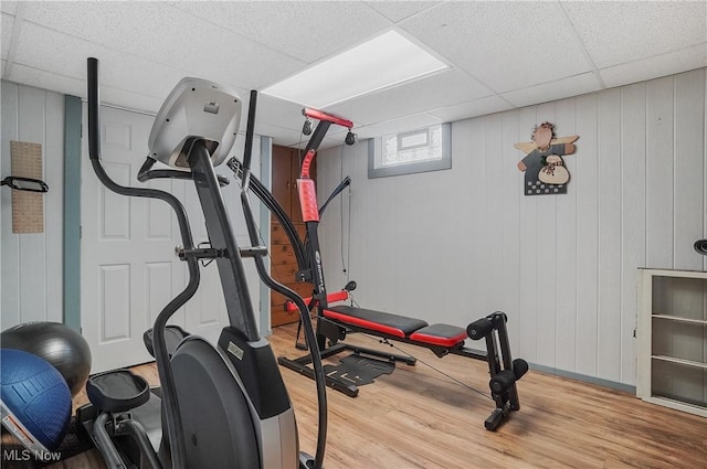 exercise room with light hardwood / wood-style flooring and a paneled ceiling