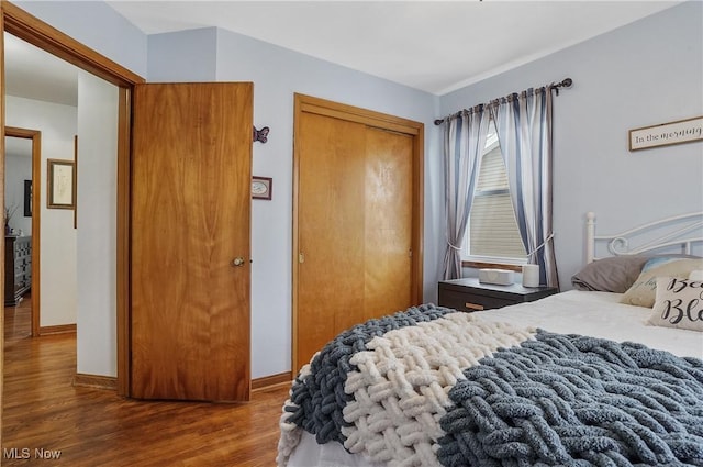 bedroom with dark wood-type flooring and a closet