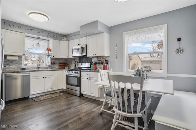 kitchen with pendant lighting, sink, appliances with stainless steel finishes, white cabinetry, and decorative backsplash