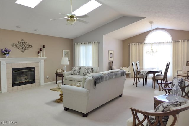 carpeted living room with ceiling fan with notable chandelier, vaulted ceiling, and a tile fireplace