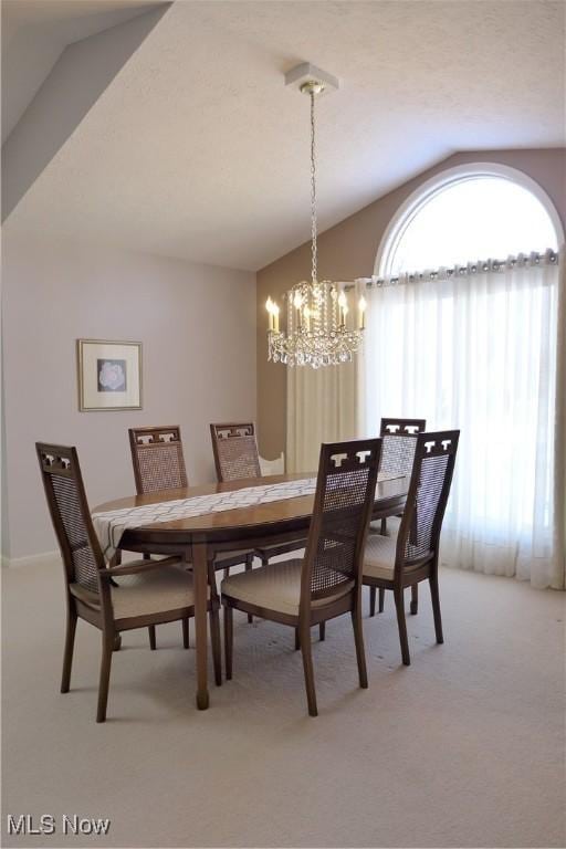 dining space with lofted ceiling, a notable chandelier, and carpet