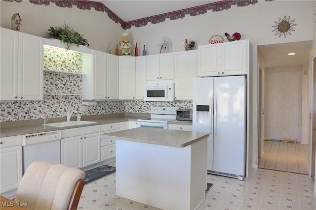 kitchen with lofted ceiling, sink, a center island, white appliances, and white cabinets