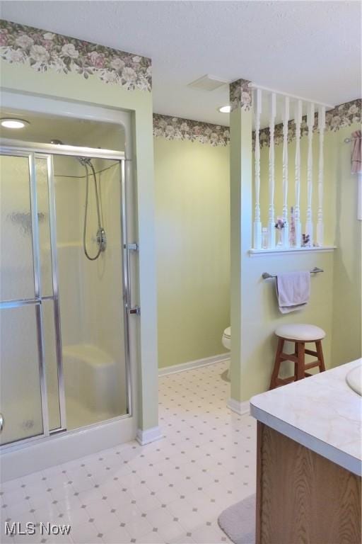 bathroom featuring vanity, toilet, and a shower with door