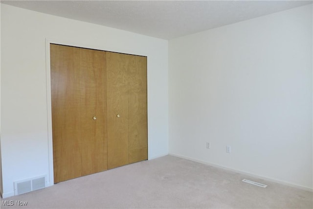 unfurnished bedroom with light colored carpet and a closet